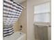 Bathroom bathtub with a striped shower curtain, grab bar, and window with blinds at 2448 Bachman Path, The Villages, FL 32162