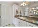 Well lit bathroom features granite countertops, cabinet storage, and a framed vanity mirror at 2448 Bachman Path, The Villages, FL 32162