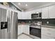 Well-equipped kitchen featuring stainless steel appliances, granite countertops, and ample white cabinetry at 2448 Bachman Path, The Villages, FL 32162