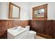 Charming bathroom with wood paneling, a decorative mirror, and a modern toilet and vanity at 263 Ne 1St St, Webster, FL 33597