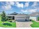 Well-maintained home exterior with a three-car garage, brick driveway, and landscaped front yard at 26601 Otter Creek Ln, Leesburg, FL 34748