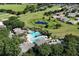 Overhead view of a community pool with palm trees, lounge chairs and a nearby pond creating a resort-like experience at 26917 White Plains Way, Leesburg, FL 34748