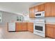 Bright kitchen featuring wooden cabinets, white appliances, and tile flooring at 2745 Shearwater St, Clermont, FL 34711
