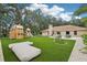 Expansive backyard featuring a playhouse, artificial turf, and comfortable seating area, perfect for Gathering fun and outdoor relaxation at 33943 E Lake Joanna Dr, Eustis, FL 32736