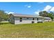 Exterior view of home showcasing green backyard, grey brick, and white window trim at 4 Kristin Ln, Eustis, FL 32726