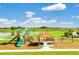Community playground with slides, swings, and picnic tables overlooking a scenic pond at 424 Noble Ave, Davenport, FL 33837