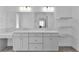 Elegant bathroom featuring dual sinks, quartz countertops, modern lighting, and open shelving at 4346 Pezzullo Cir, The Villages, FL 32163