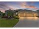 Charming single-story home with a well-manicured lawn, lovely landscaping, and a spacious driveway at sunset at 4346 Pezzullo Cir, The Villages, FL 32163