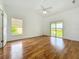 Bright bedroom with hardwood floors, a ceiling fan, and a sliding glass door leading to a backyard view at 439 Gentle Breeze Dr, Minneola, FL 34715