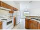 Functional kitchen with wooden cabinets, white appliances, and a view of the backyard, ready for your culinary creations at 439 Gentle Breeze Dr, Minneola, FL 34715