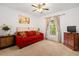 Cozy bedroom featuring a red sofa, ceiling fan, and neutral carpet. Opens onto a patio at 5144 Rishley Run Way, Mount Dora, FL 32757