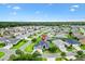 An aerial view shows this home in a neighborhood setting with lawns, palm trees, and mature trees at 5868 Wood Stork Way, The Villages, FL 32163
