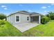 View of the backyard of the home with a screened lanai and concrete patio, surrounded by green grass at 5868 Wood Stork Way, The Villages, FL 32163
