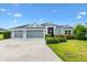 Charming single-story home with a well-manicured lawn, a three-car garage, and a welcoming front entrance at 5868 Wood Stork Way, The Villages, FL 32163
