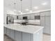 Bright kitchen features gray cabinets, stainless steel appliances, and an island with white countertops and pendant lighting at 5868 Wood Stork Way, The Villages, FL 32163