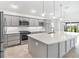 Modern kitchen featuring sleek gray cabinets, a large island, stainless steel appliances, and elegant pendant lighting at 5868 Wood Stork Way, The Villages, FL 32163
