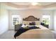 Relaxing primary bedroom boasts tray ceiling, large windows, and a comfortable bed with stylish linens at 6301 Danielson Loop, The Villages, FL 32163