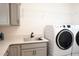 Well-equipped laundry room with a sink, counter space, cabinetry, and modern washer and dryer units at 6301 Danielson Loop, The Villages, FL 32163