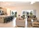 Open-concept living room with kitchen island, seating, and sliding doors to the patio at 6301 Danielson Loop, The Villages, FL 32163