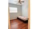 A simple bedroom with a ceiling fan, wood floors, and a bright window providing natural light at 679 Avenue Q Se, Winter Haven, FL 33880