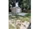 Exterior view of a metal storage shed with double doors, a concrete pad, and a wooded backyard at 679 Avenue Q Se, Winter Haven, FL 33880