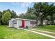 Lovely single story home featuring a red door, tidy landscaping, and mature trees at 780 N Kentucky Ave, Umatilla, FL 32784