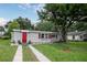 Charming single story home with red door and shutters, and a well-maintained lawn at 780 N Kentucky Ave, Umatilla, FL 32784