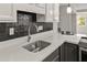 Clean and modern kitchen featuring a stainless steel sink, quartz countertops, and black backsplash at 780 N Kentucky Ave, Umatilla, FL 32784