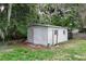 Exterior view of a shed in the backyard with mature trees and a grassy area at 780 N Kentucky Ave, Umatilla, FL 32784