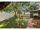 Large, grassy backyard with mature trees, white fence, and a patio with screened-in porch at 800 Daybreak Dr, Fruitland Park, FL 34731