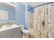 Bathroom featuring blue walls, gray vanity, decorative mirror and tub with shower at 800 Daybreak Dr, Fruitland Park, FL 34731