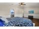 Comfortable bedroom with wood floors, TV, ceiling fan, walk in access to a bathroom, and blue decorative comforter at 800 Daybreak Dr, Fruitland Park, FL 34731