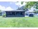 View of the home's backyard with a screened lanai, patio and a well-maintained lawn at 8489 Se 158Th Pl, Summerfield, FL 34491