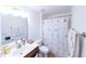 Bright bathroom with a single sink vanity, toilet, shower with curtain and floral pattern at 8489 Se 158Th Pl, Summerfield, FL 34491