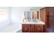 Bathroom featuring a soaking tub, double sink vanity with dark wood cabinetry, and bright lighting at 8489 Se 158Th Pl, Summerfield, FL 34491