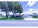 Inviting single-story home with lush front lawn, mature trees, and a spacious driveway leading to the garage at 8489 Se 158Th Pl, Summerfield, FL 34491