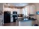 Well-lit kitchen featuring white cabinets, a black refrigerator, and an island with dark countertops at 9219 Chandler Dr, Groveland, FL 34736