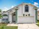 A white and green two-story home with a two-car garage features manicured landscaping and an inviting entrance at 1034 Copenhagen Way, Winter Garden, FL 34787