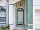 The front porch features a white door with green trim, an overhead light, decorative tiles, and a welcoming entrance at 1034 Copenhagen Way, Winter Garden, FL 34787