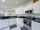 Bright kitchen featuring white cabinetry, black countertops and stainless steel appliances at 1034 Copenhagen Way, Winter Garden, FL 34787