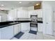 Bright kitchen featuring white cabinetry, black countertops and stainless steel appliances at 1034 Copenhagen Way, Winter Garden, FL 34787