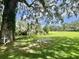 Scenic landscape with a bench under a large tree with Spanish moss near a tranquil pond at 105 Avocado Cv, Leesburg, FL 34748