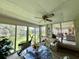 Bright sun room with a ceiling fan, glass table and views of the backyard and pond at 105 Avocado Cv, Leesburg, FL 34748