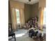 Bedroom featuring natural light from large windows, aged walls, and a substantial collection of books stacked high at 110 S Trowell Ave, Umatilla, FL 32784