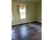 Bedroom view showing damaged wood floor, aged window trim and drab walls, awaiting renovation at 110 S Trowell Ave, Umatilla, FL 32784