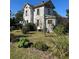 Full view of a two-story home set in an overgrown yard with bushes at 110 S Trowell Ave, Umatilla, FL 32784