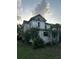 Side angle of a two-story home with a covered porch, set amongst mature trees and landscaping needing repair at 110 S Trowell Ave, Umatilla, FL 32784