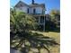 Two-story home with porch surrounded by a verdant lawn with palm trees and flowering bushes at 110 S Trowell Ave, Umatilla, FL 32784