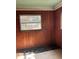 Room featuring wood-paneled walls, a window with natural light, and worn flooring at 110 S Trowell Ave, Umatilla, FL 32784