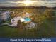 Aerial view showcasing a resort-style community with a pool, clubhouse, and lush landscaping at sunset at 1180 Mesa Verde Ct, Clermont, FL 34711